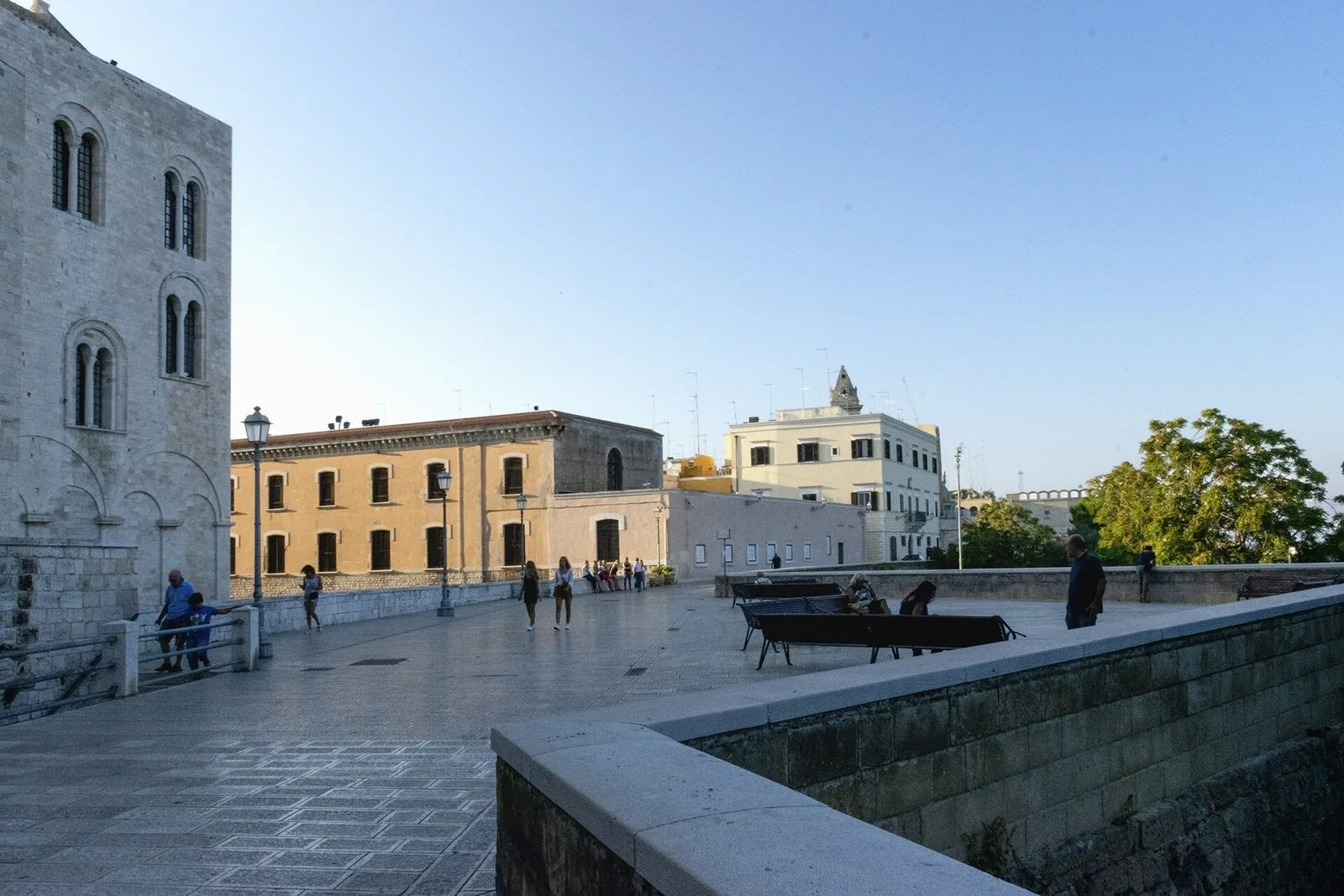 La passeggiata sulla Muraglia di Bari Vecchia, con le mura in pietra, i lampioni e gli edifici storici della città vecchia sotto il cielo azzurro