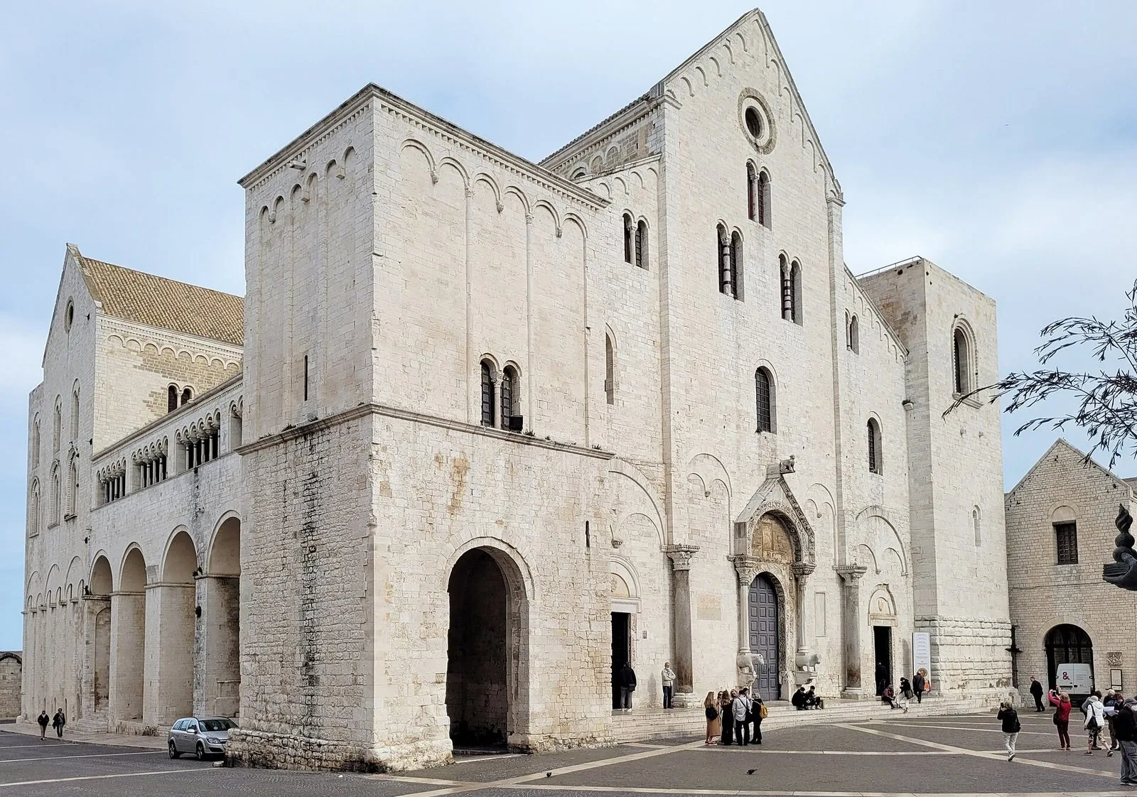 La facciata in pietra chiara della Basilica di San Nicola a Bari, con le due torri laterali e la piazza davanti