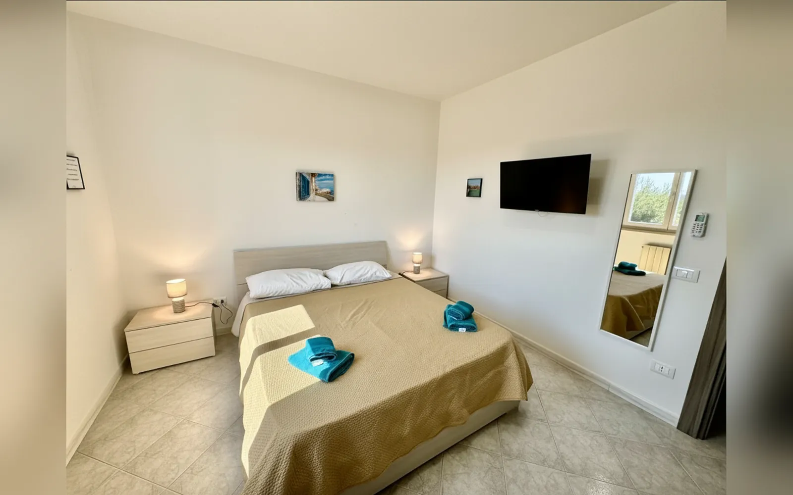La camera matrimoniale con il letto, la TV a parete e lo specchio